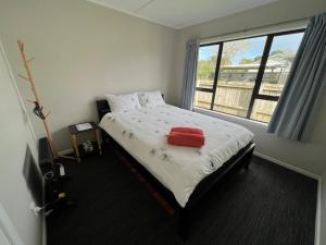 ein Schlafzimmer mit einem Bett mit einem roten Handtuch darauf in der Unterkunft Yucca Home in Auckland