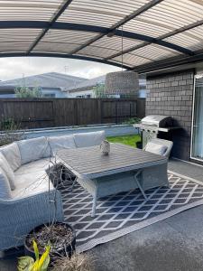 a patio with a couch and a table and a grill at Lakes Executive Suites in Tauranga
