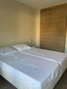 ein weißes Bett in einem Schlafzimmer mit einem Holzschrank in der Unterkunft Superbe appartement st mandrier à 100mde la plage in Saint-Mandrier-sur-Mer