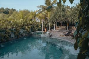 a woman is standing next to a swimming pool at Mangroove Bay Boutique Hostel in Banyuwedang