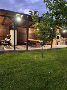 a house with a patio with a tree in the yard at Casa de vacanta TARA in Eşelniţa
