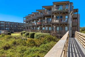 a building with balconies and a walkway in front of it at Oceanfront Shared Pool C102A Sea over the Dune in Duck
