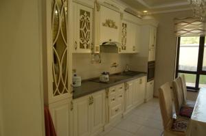 una cucina con armadi bianchi, lavandino e finestra di Guest House Nazmir 