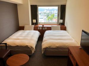 um quarto de hotel com duas camas e uma janela em Dormy Inn Kurashiki Natural Hot Spring em Kurashiki