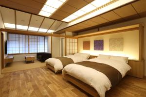 a bedroom with two beds in a room with windows at Shoenso Hozugawatei in Kameoka