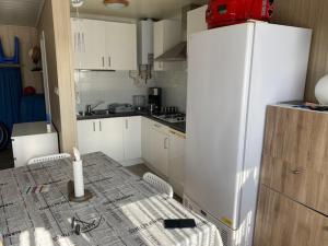 a kitchen with white cabinets and a white refrigerator at Camping Esmeralda in De Haan