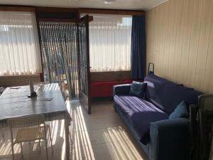 Camping Esmeralda في دي هان: غرفة معيشة مع أريكة أرجوانية وطاولة