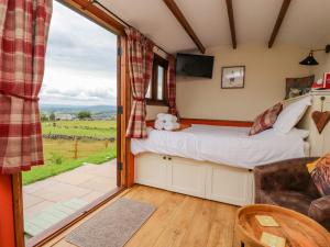 a bedroom with a bed and a sliding glass door at The Herdsman Luxury Shepherds Hut in Barnoldswick