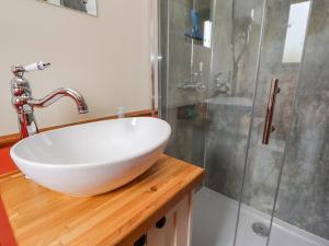 a bathroom with a white sink and a shower at The Herdsman Luxury Shepherds Hut in Barnoldswick