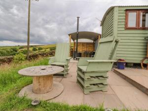 two chairs and a table in front of a house at The Herdsman Luxury Shepherds Hut in Barnoldswick
