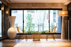 a lobby with a table and chairs and a large window at Tomariehotel & condominium in Fukuoka