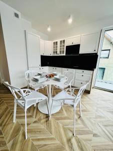 a white dining room with a white table and chairs at SunBaltic Premium Ustka, II Poziomy, Przy Lesie, Dwa Balkony, Klimatyzacja, Parking in Ustka