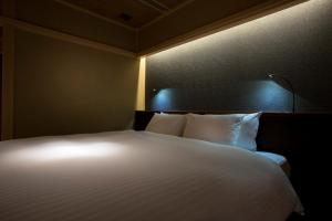 1 cama con almohadas blancas en una habitación en Hotel Yuraku Kyo-yasaka, en Giommachi