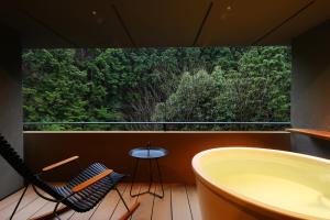 a bathroom with a tub and a table and a window at Shoenso Hozugawatei in Kameoka