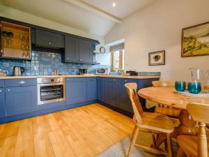 kuchnia z niebieskimi szafkami i drewnianym stołem w obiekcie Shepherds Cottage w mieście Ambleside