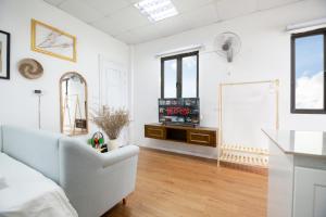 een witte woonkamer met een bank en een tv bij Capital CauGiay Hotel in Hanoi