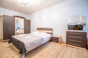 a bedroom with a bed and a dresser and a television at GuestHouse NaSHGOBI in Ushguli