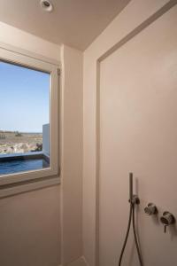 a bathroom with a window and a shower at Acanthus Oia - Suites With Private Hot Tub in Oia