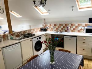 eine Küche mit einem Tisch mit einer Vase mit Blumen darauf in der Unterkunft Cloister Park Cottages in Frithelstock + 15 Fotos