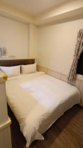 a large white bed in a room with a window at Galaxy Mini Inn in Taipei