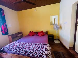 NEW ORGANIC HOME STAY في Mudigere: غرفة نوم بسرير ومخدات حمراء ومروحة
