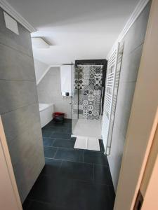 uma casa de banho com chuveiro e piso em azulejo preto em Sana em Postojna