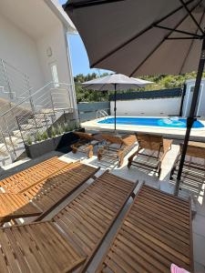 a patio with chairs and an umbrella and a swimming pool at Villa Milena Sweet apartment-with a pool in Trogir