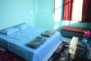 a bedroom with a blue bed and a glass table at H P HomeStay in Dhārwād