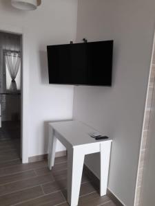 una mesa blanca con TV en una pared blanca en B&B Green House, en Villapiana