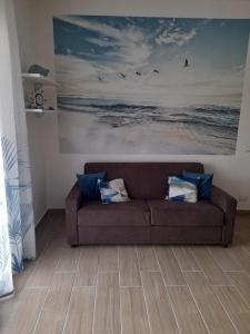 ein braunes Sofa im Wohnzimmer mit einem Gemälde in der Unterkunft B&B Green House in Villapiana