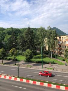 Une voiture rouge descend dans une rue dans l'établissement Central Apartment 4 Rooms Brasov, à Braşov