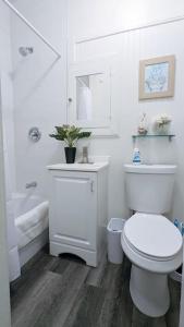 a white bathroom with a toilet and a bath tub at Metro Paris - 3 Day Minimum - Secluded Studio near the Long Beach Harbor in Long Beach