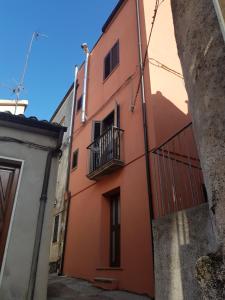 un bâtiment rouge avec un balcon dans une ruelle dans l'établissement Quiete del Sirino, à Moliterno