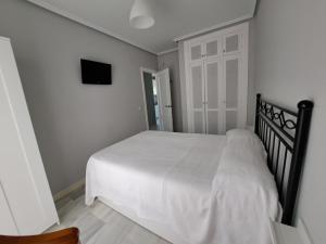 um quarto com uma cama branca e uma televisão em Apartamento Pinares del atlantico em Chiclana de la Frontera