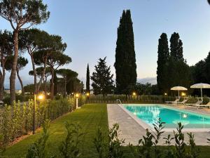 a swimming pool in a garden with trees and lights at La Vecchia cantina Guzzardi in Lari