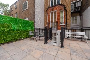 um pátio com dois bancos, uma mesa e cadeiras em Kensington luxury flat with patio em Londres