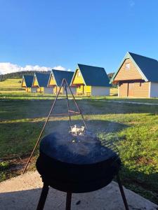 a bbq grill in a field with houses in the background at Vule bungalovi in Žabljak