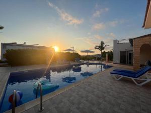 a swimming pool with a sunset in the background at Villa Imperial Sea-Caves Private Pool in Peyia
