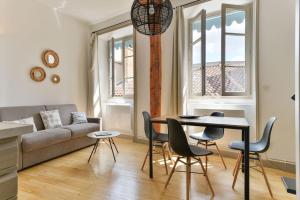 een woonkamer met een bank en een tafel en stoelen bij Les jardins du Gourguillon in Lyon