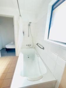 a white bathroom with a tub and a shower at Jacaranda Place Motor Inn in Toowoomba