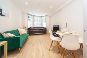 a living room with a green couch and a table at Kensington luxury flat with patio in London