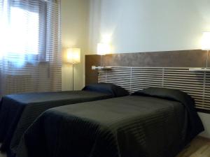una camera da letto con due letti e due luci sul muro di Ai Gabbiani a Verona