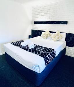 a bedroom with a large bed with white sheets and pillows at Jacaranda Place Motor Inn in Toowoomba