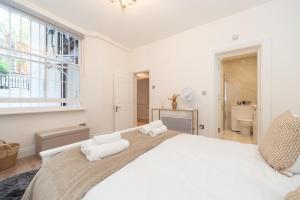 a white bedroom with a large bed and a window at Kensington luxury flat with patio in London