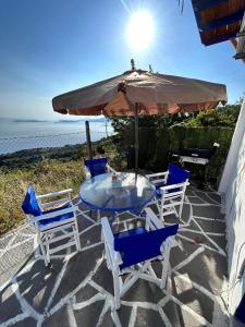 patio con tavolo, sedie e ombrellone di Avgoustina's Home a Glossa
