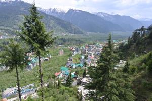 a town in a valley with trees and mountains at Hotel Seven Hills Manali in Manāli