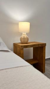 a table with a lamp on it next to a bed at Dimora Donna Vitalia Apartments in Erice