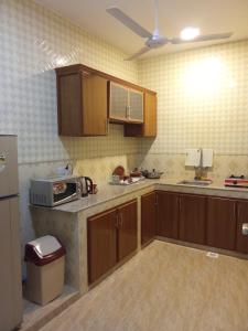 an empty kitchen with wooden cabinets and a microwave at Argaan Apartment in Salalah