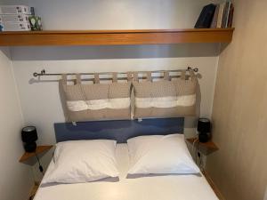 1 Schlafzimmer mit einem Bett mit blauem Kopfteil und 2 Kissen in der Unterkunft Charmant Mobil-home climatisé avec 2 chambres et entièrement équipé, sauf draps en option, pour 5 personnes au maximum in Sarlat-la-Canéda