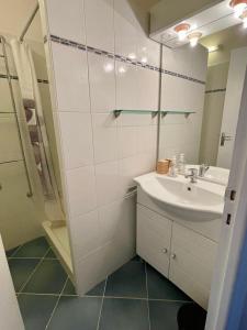 ein weißes Badezimmer mit einem Waschbecken und einem Spiegel in der Unterkunft L’échappée Belle in Orcières